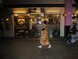 Uma maiko andando perto de seu trabalho em Gion Kobu, Quioto.